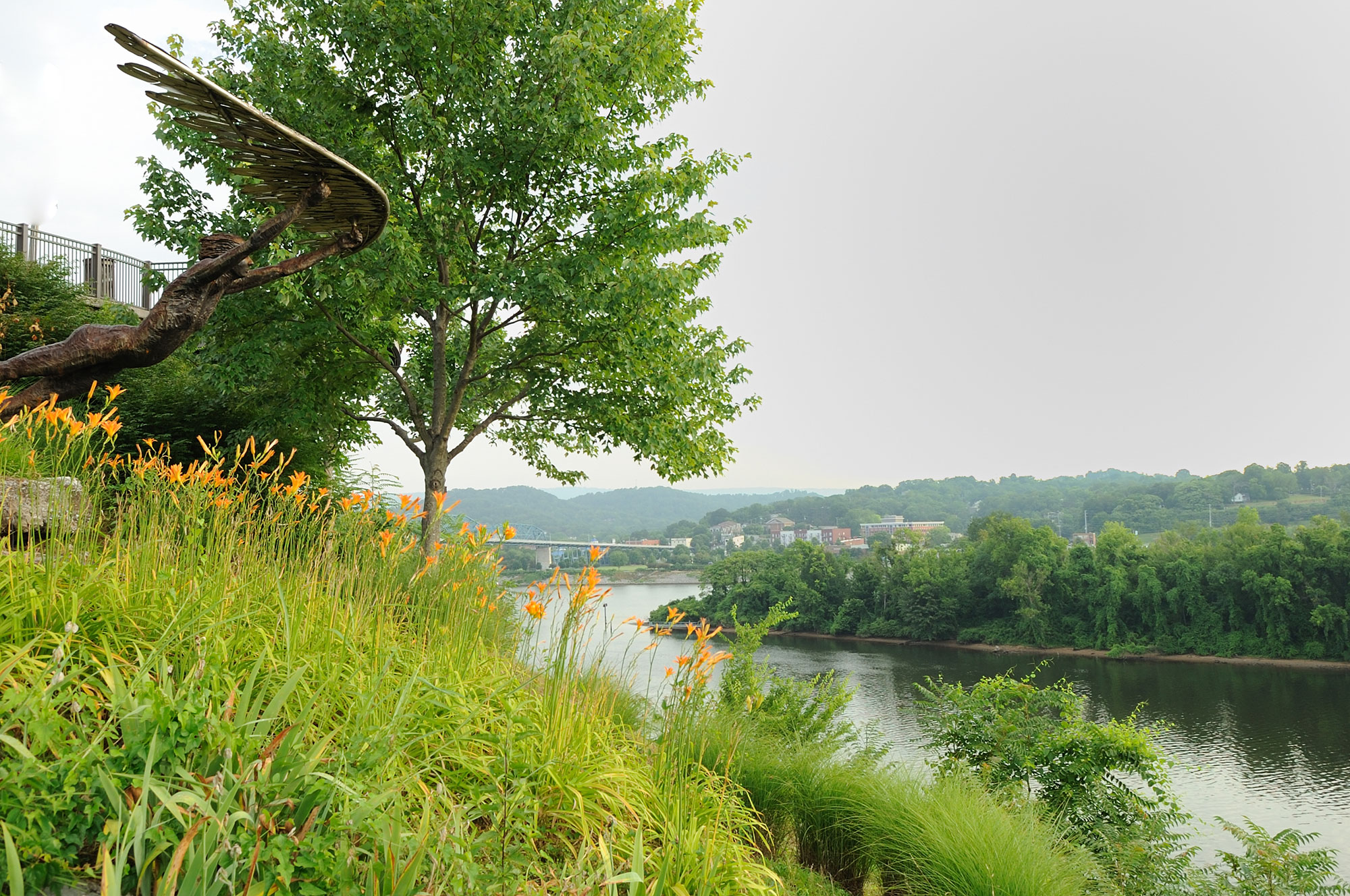 A statue of an eagle on top of a hill next to a river.