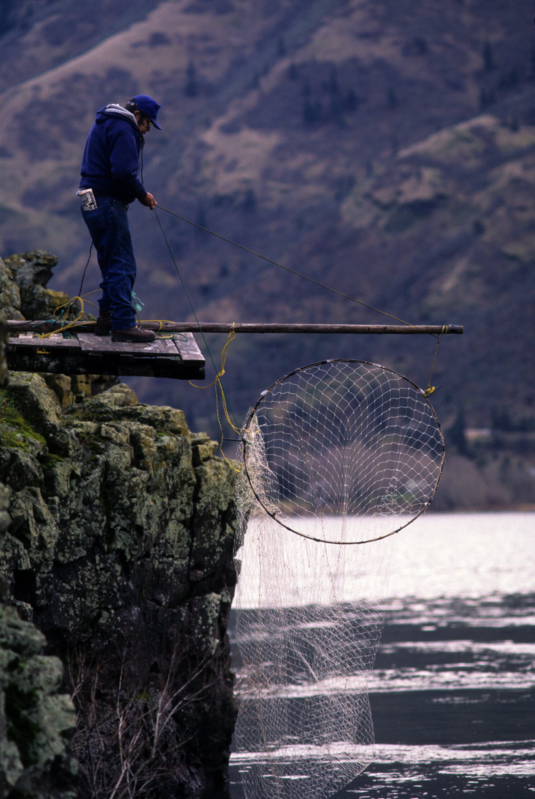 A man standing on a cliff with a fishing net.