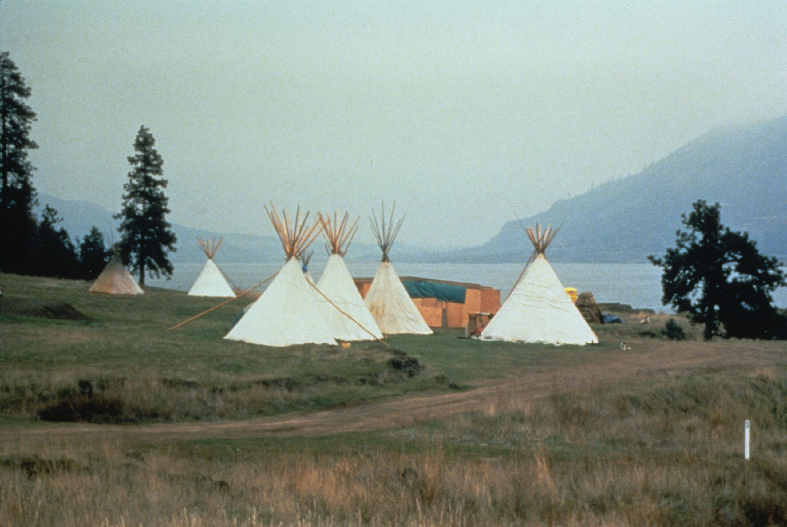 A group of teepees next to a lake.