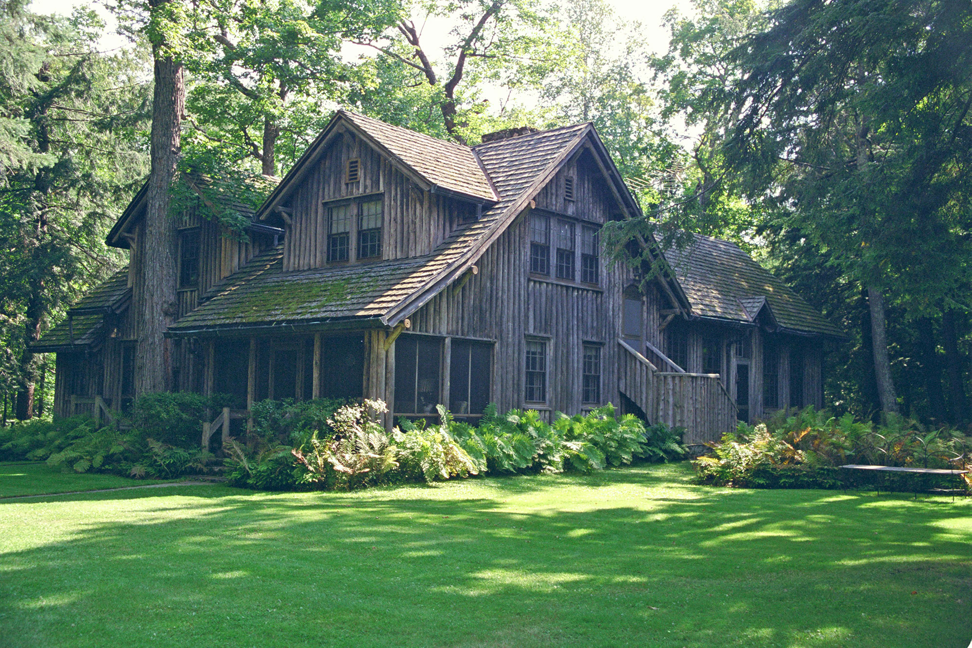 A wooden house surrounded by green grass and trees.