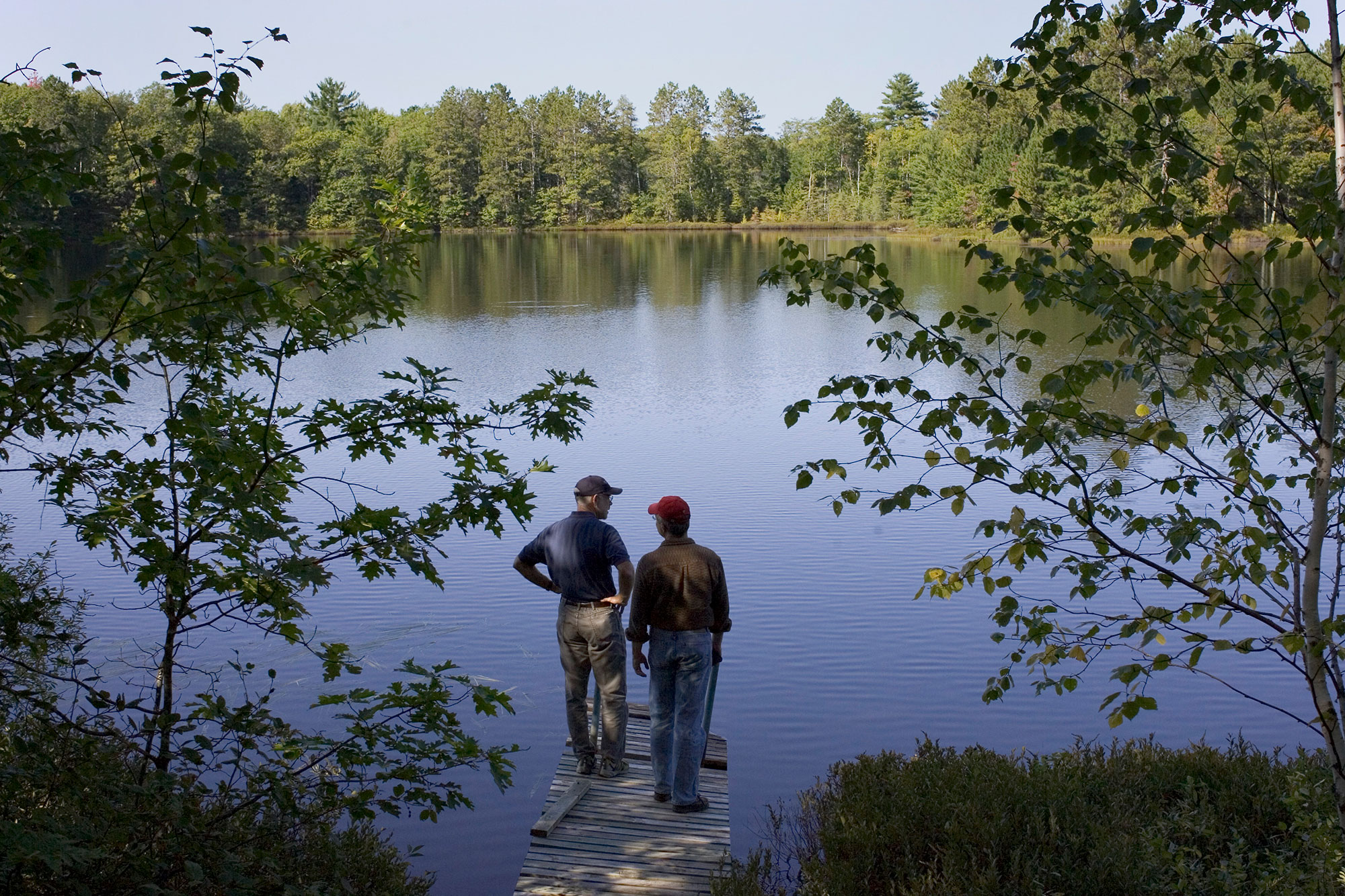 Two men standing on a dock near a lake.