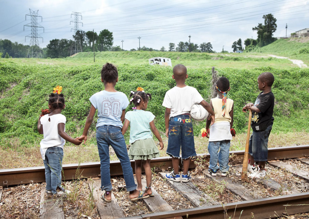 A group of children standing on a train track.
