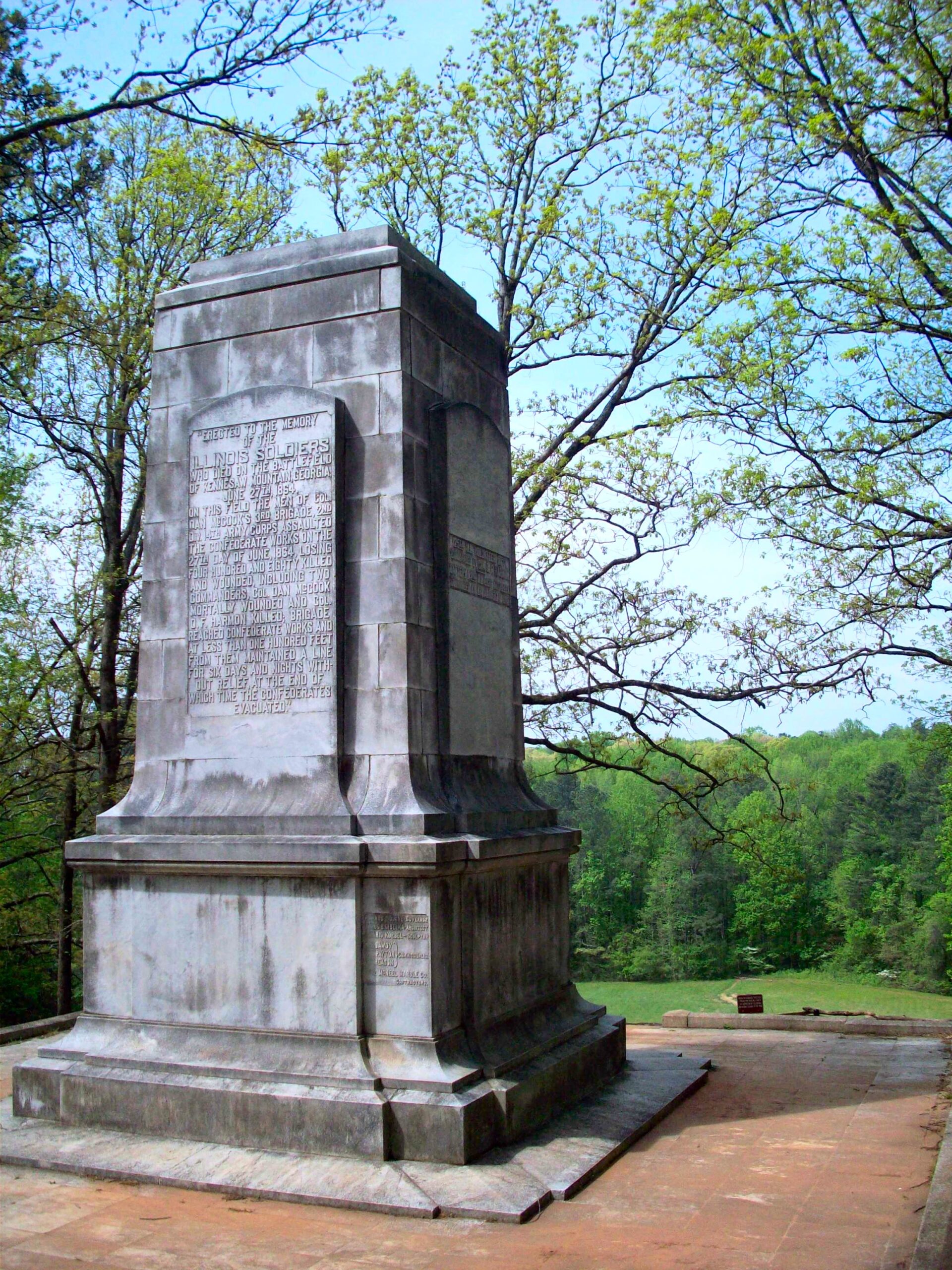 A monument sits in the middle of a wooded area.