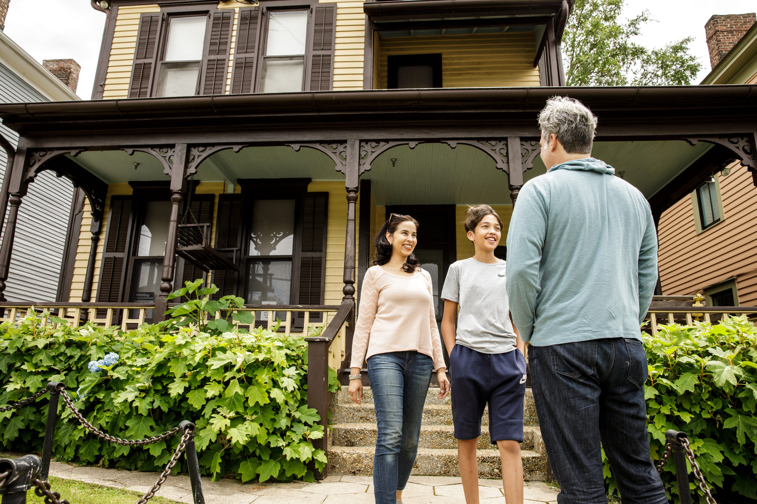 Three people standing in front of a house.