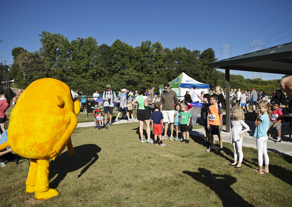 A yellow mascot is standing in front of a crowd of people.