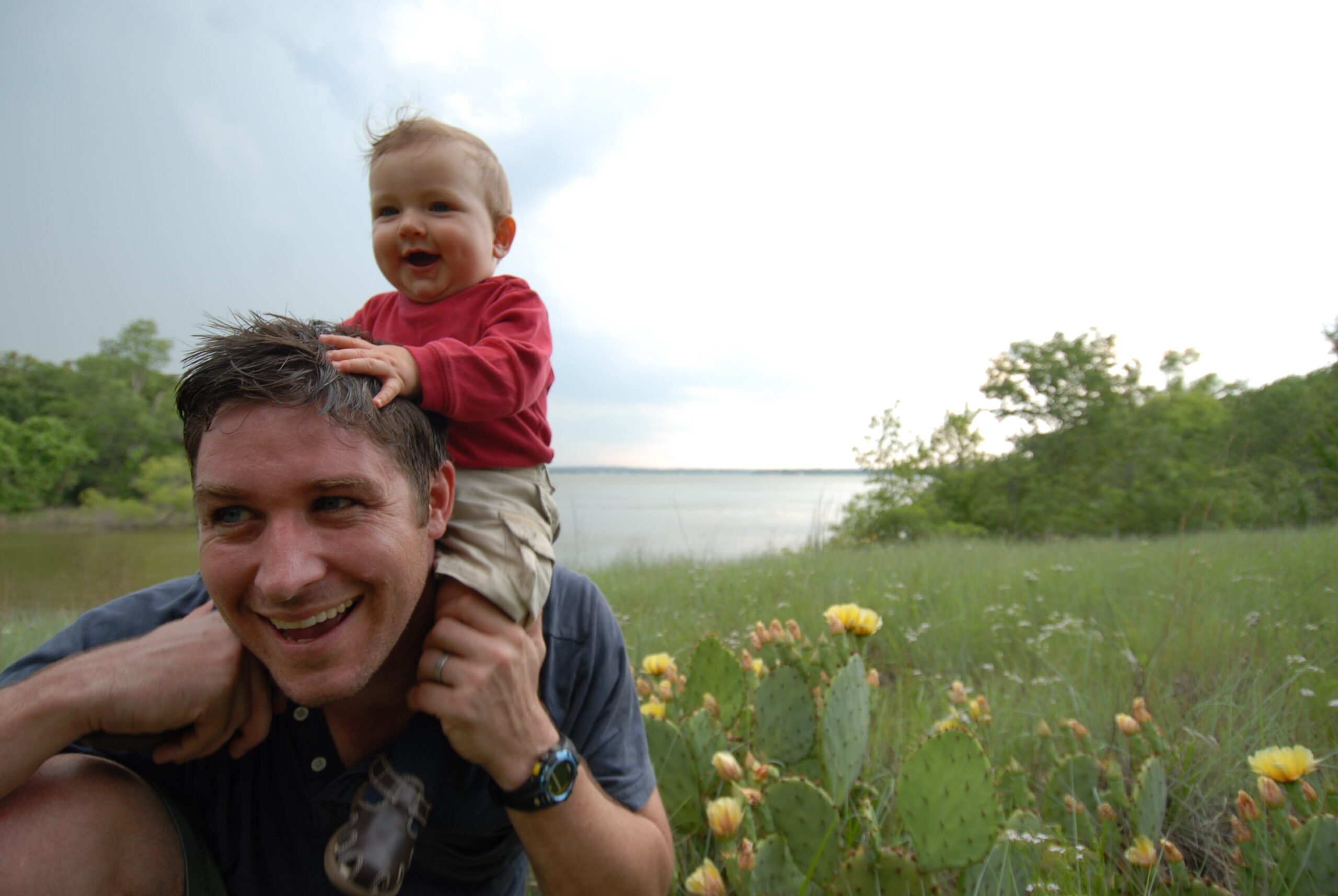 A man holding a child in front of a lake.