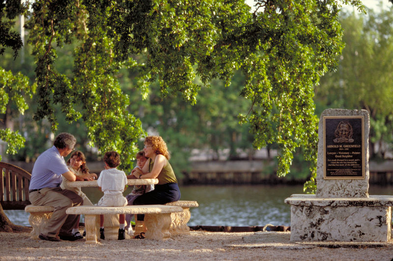 A group of people sitting at a picnic table near a body of water.