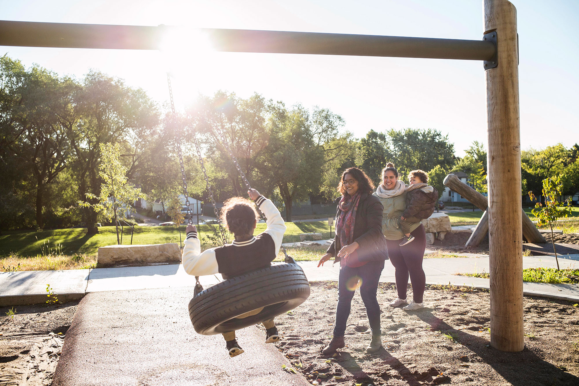 A group of people playing on a swing at a playground.