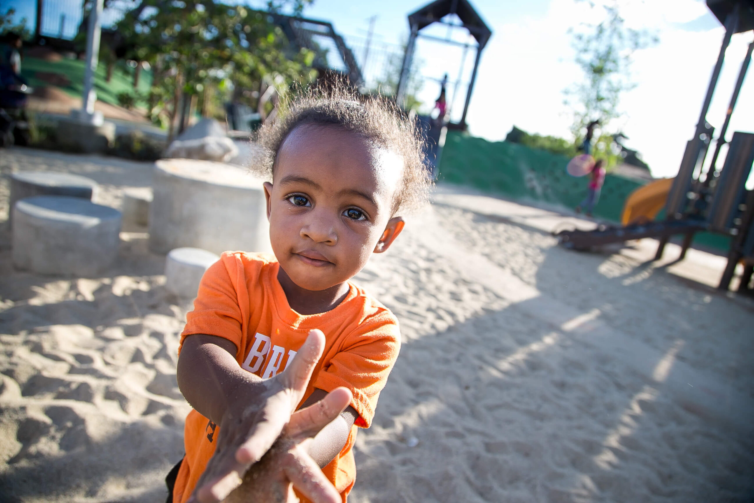 A young boy is playing in the sand at a playground.