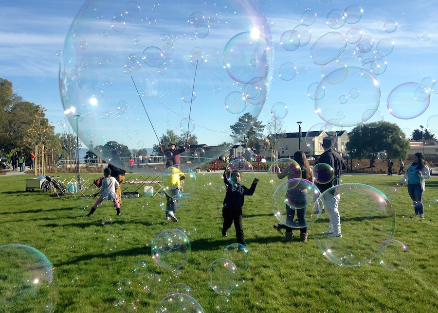 Children play on the grass at Hilltop Park amidst giant soap bubbles
