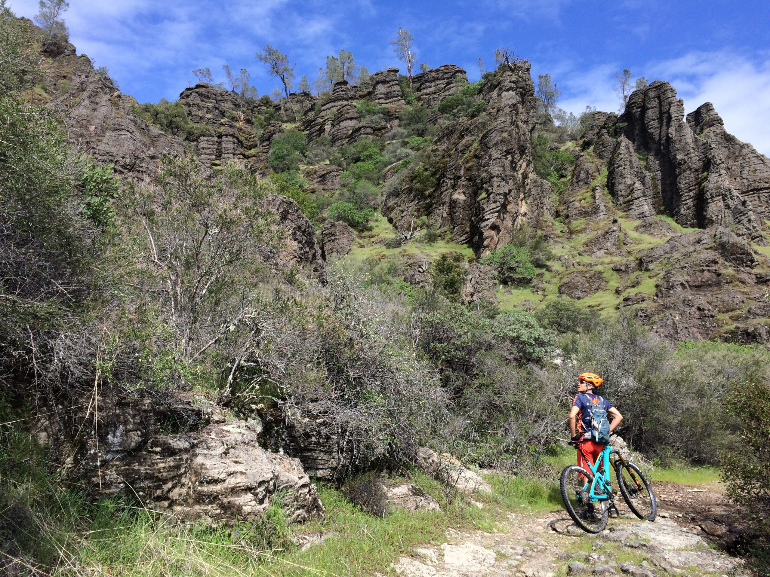 A mountain biker looks up at a rock formation
