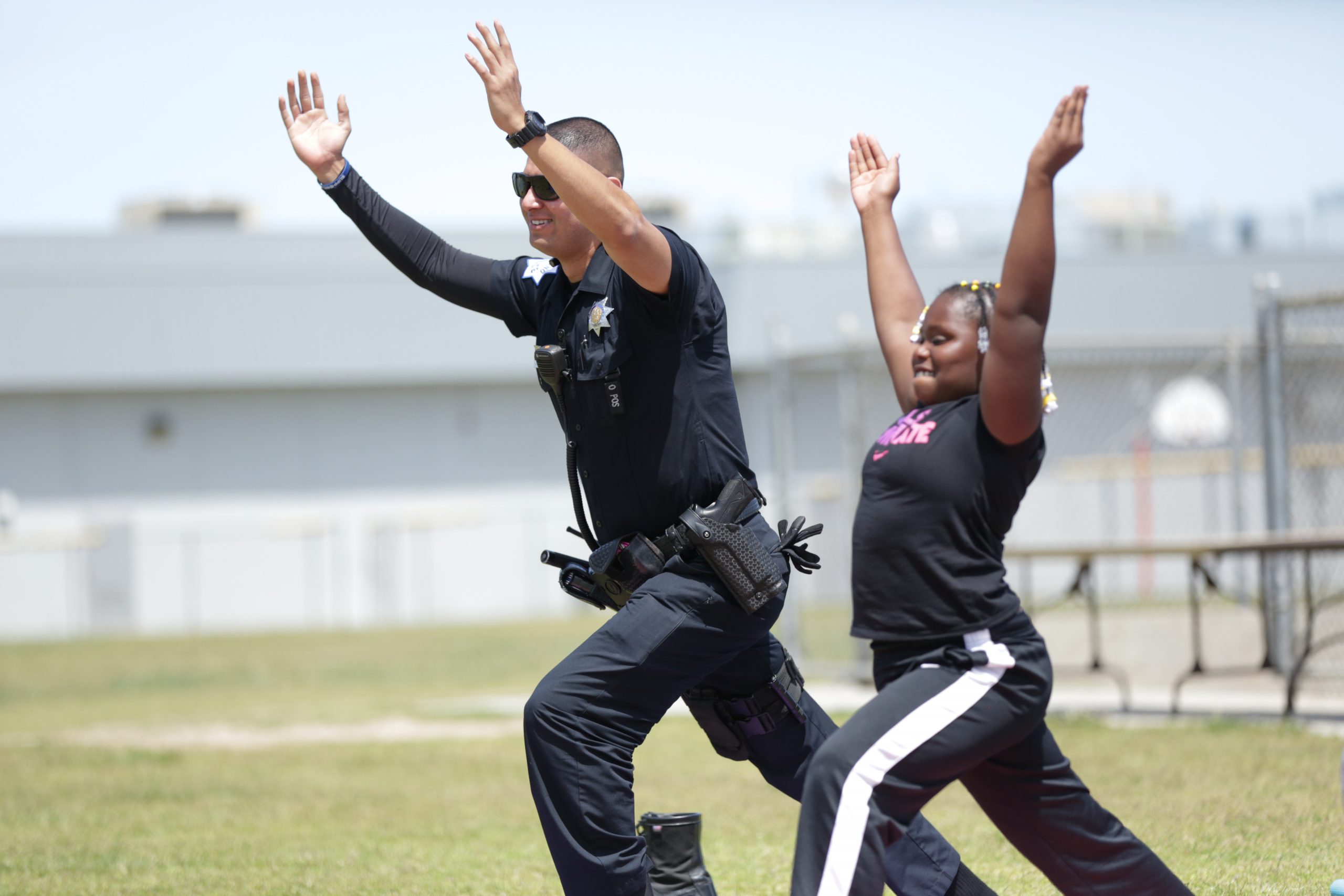 A policeman and a kid do yoga in a schoolyard
