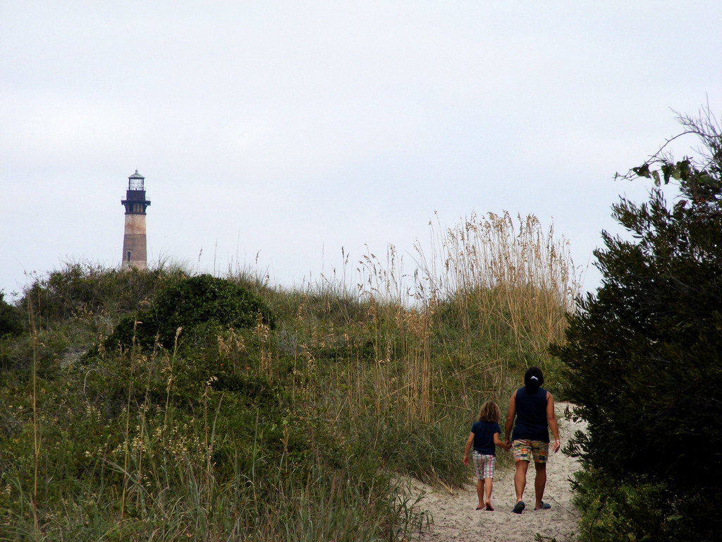 A mom and child walk toward the lighthouse on Morris Island