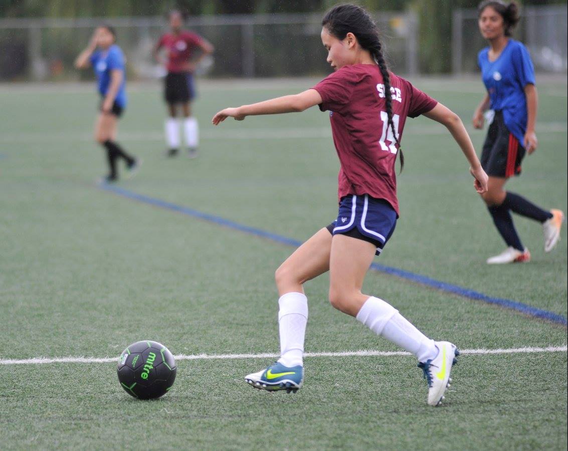 A young woman kicks a soccer ball