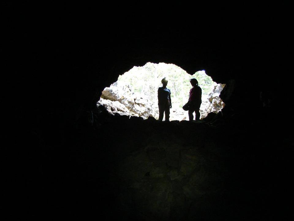 Two silhouetted figures in the mouth of a cave