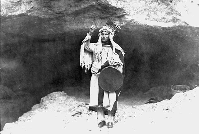 A Dakota man stands at the mouth of a cave in an old photo