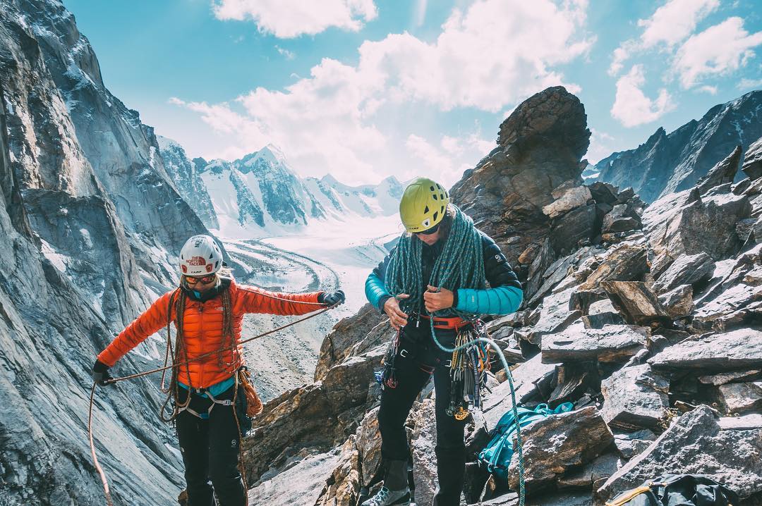 Two women climb above a glaciated valley