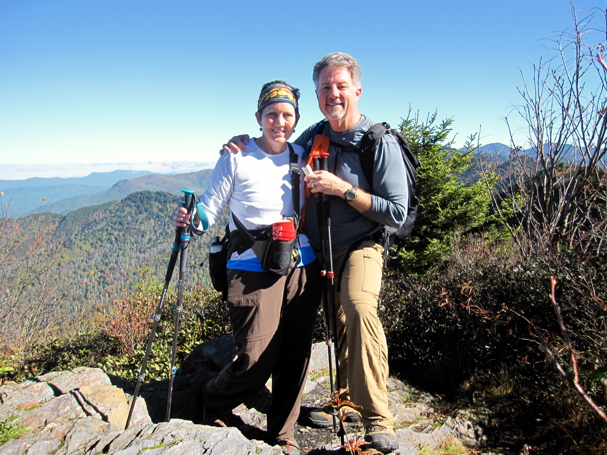 A couple pose on a mountain top