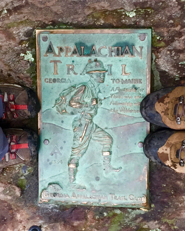 Two sets of boots stand on a plaque announcing the southern end of the Appalachian Trail