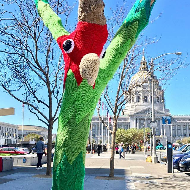 A knit parrot clings to a tree