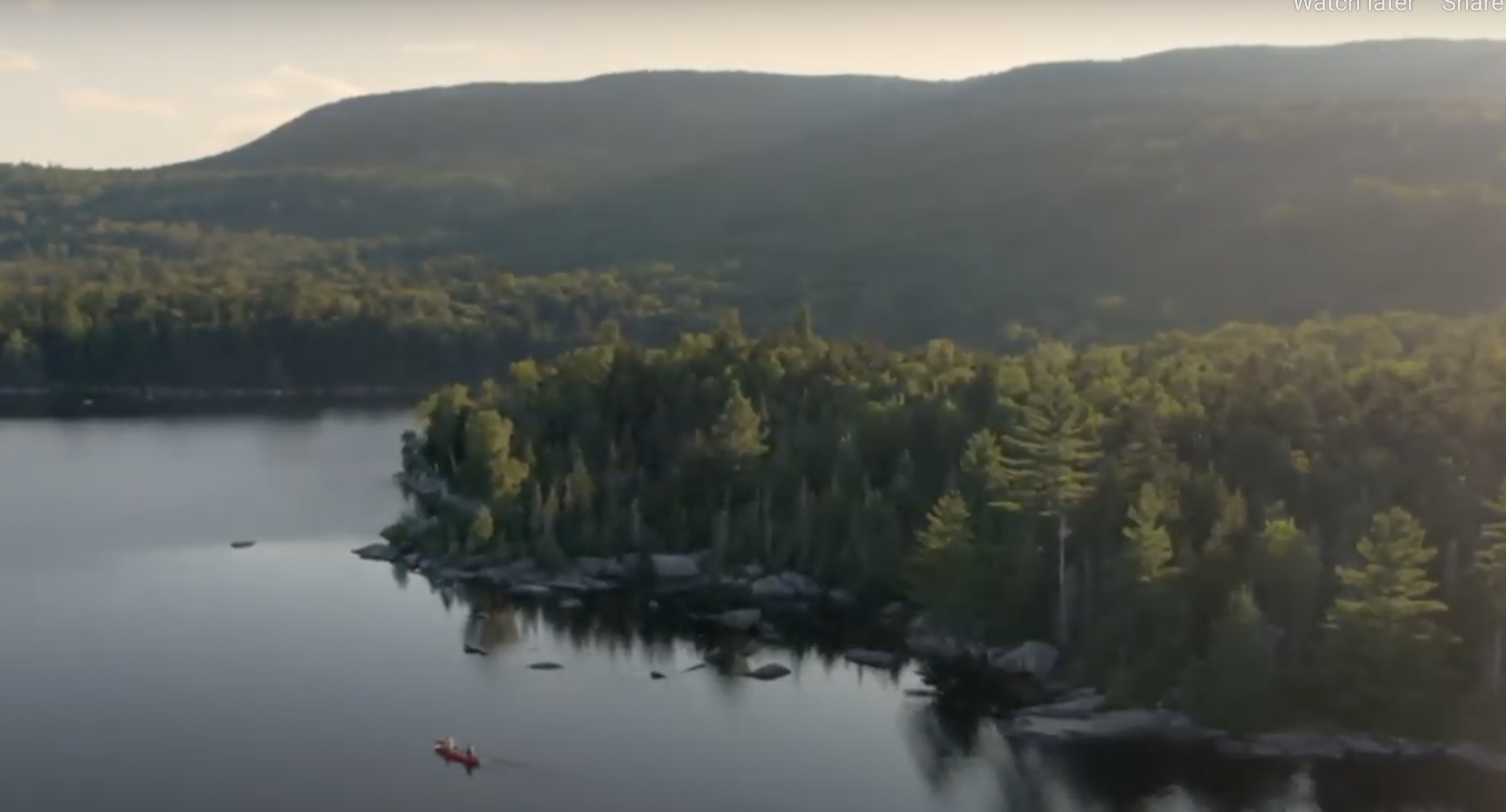 An aerial view of a lake with a canoe on it.