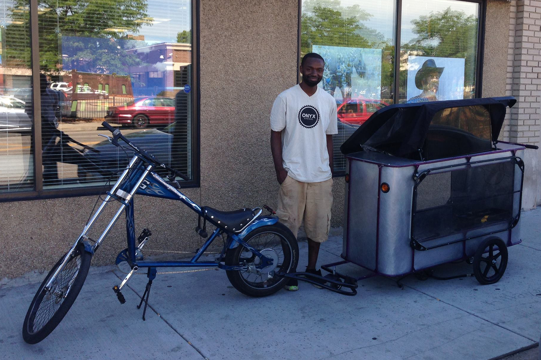 A man stands in front of a bicycle pulling a trailer