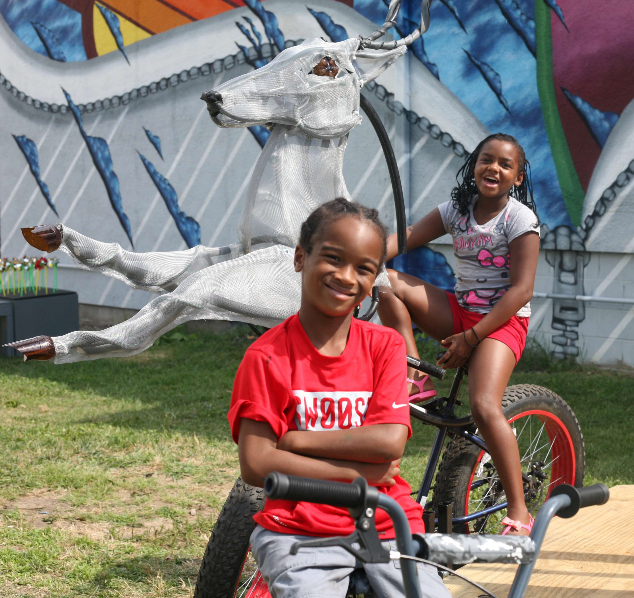 Two kids sit on a bike carousel