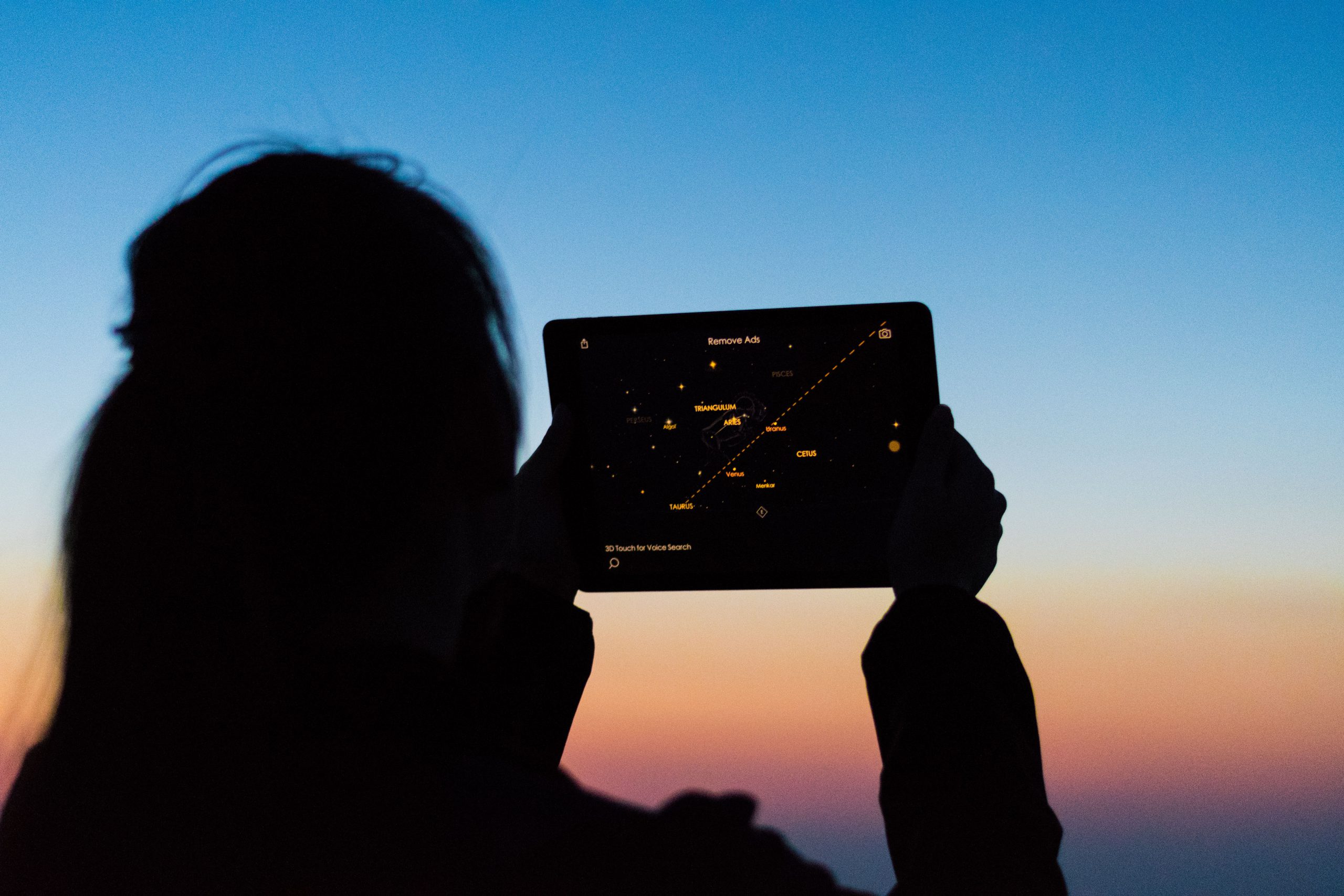 A woman looks at the sky using a star app on a tablet