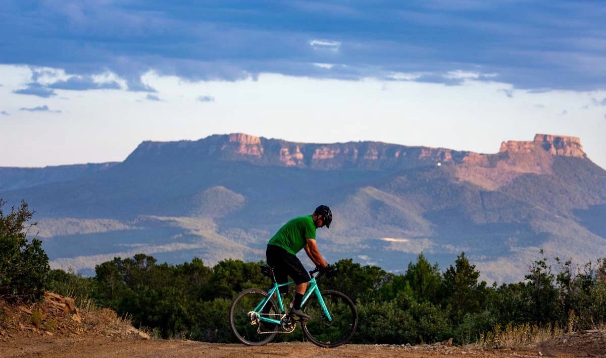 Juan De La Roca rides a mountain bike with Fisher's Peak in the background