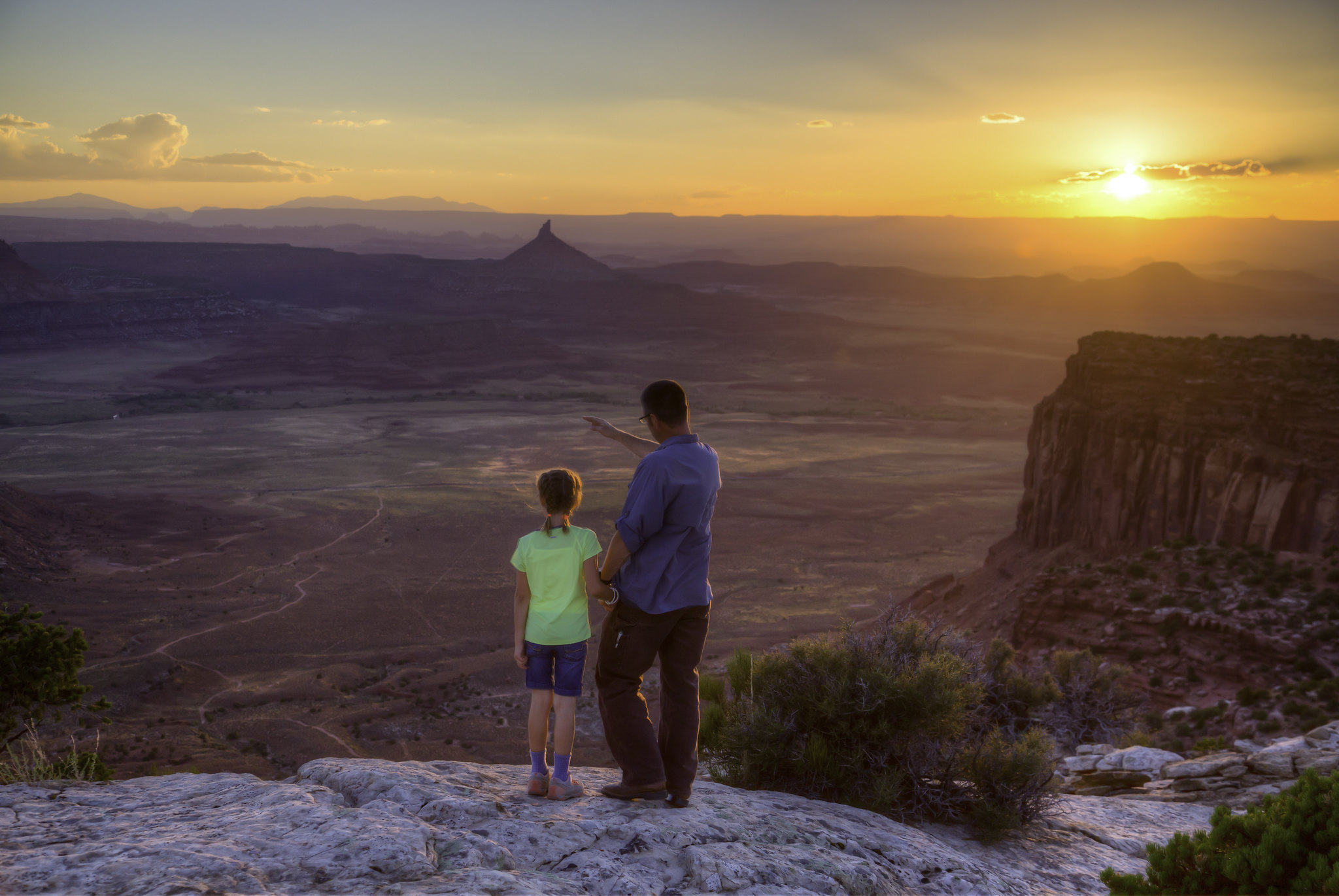 A father and daughter stand on an overlook at Indian Creek in Bears Ears National Monument at sunset