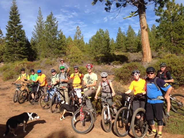 A group of people on mountain bikes poses for the camera