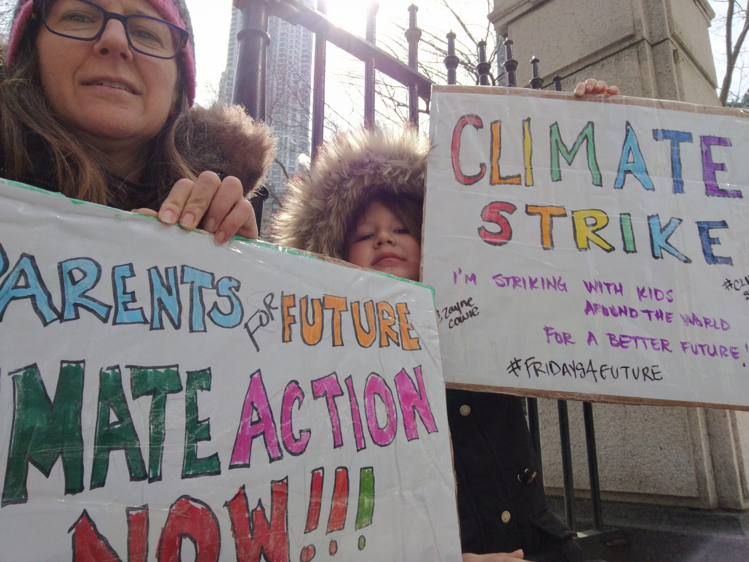 A mom and son hold climate strike signs wearing winter coats