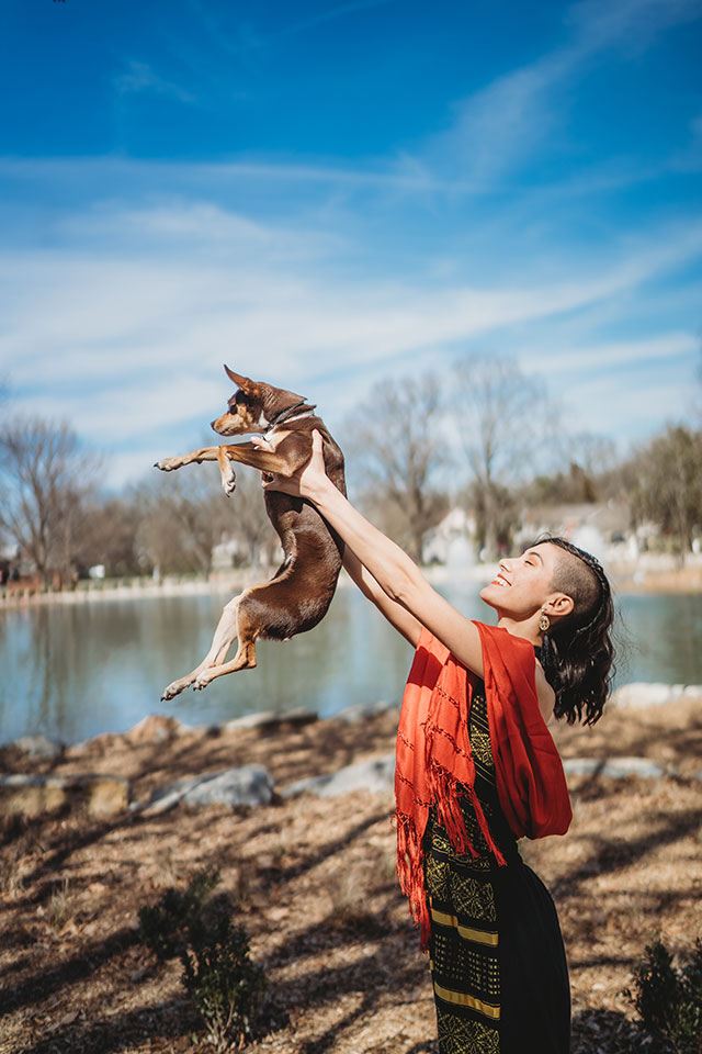 A woman is holding a dog in the air.