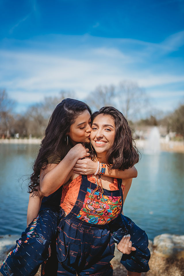 Two women hugging in front of a pond.