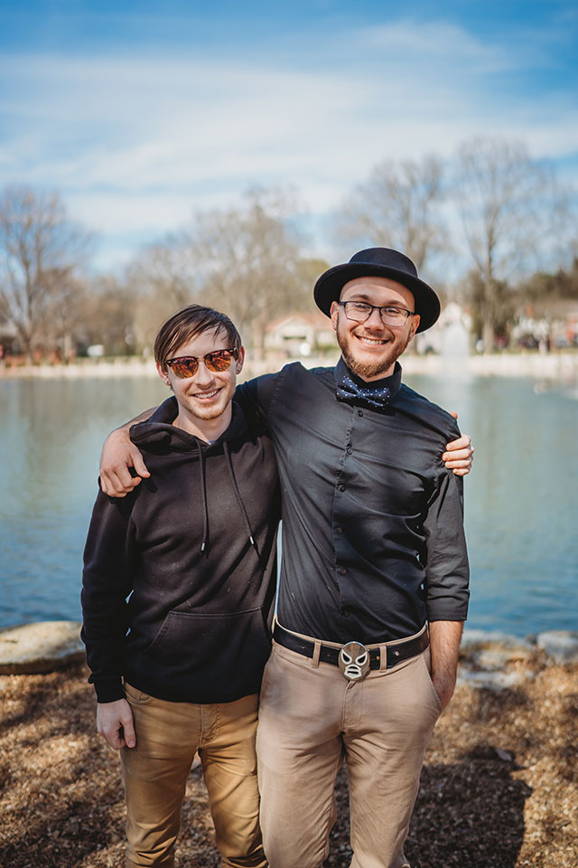 Two men posing for a photo in front of a pond.