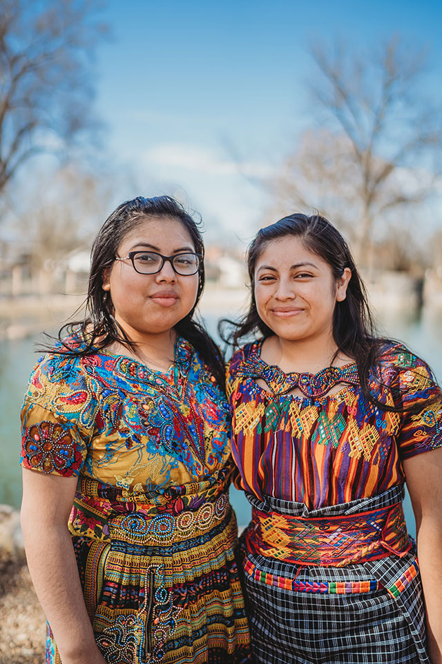 Two mexican women standing in front of a pond.