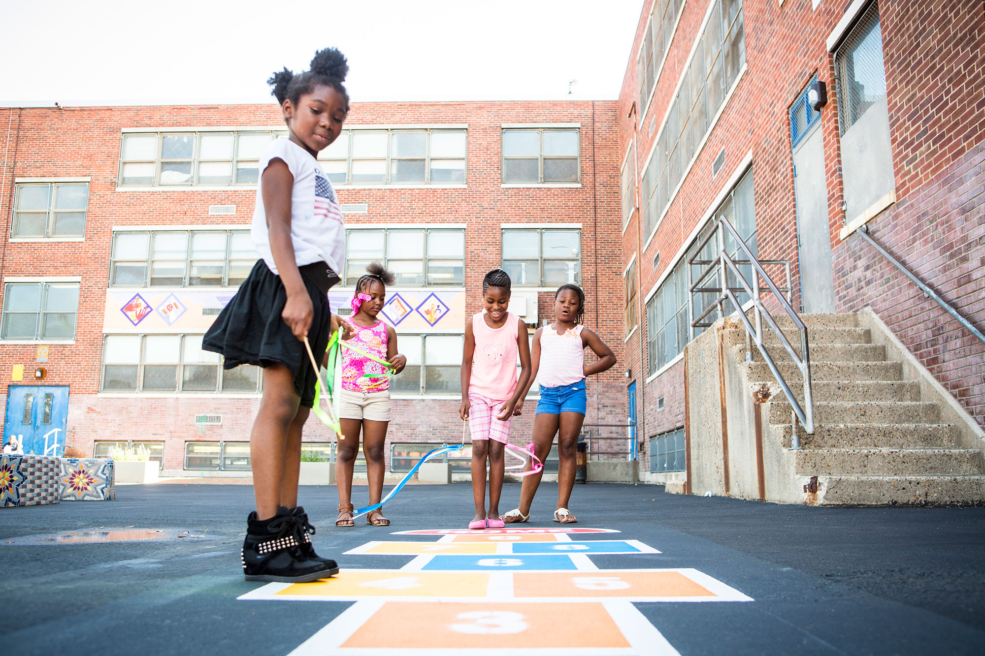 A group of young girls playing hopscotch on a sidewalk.