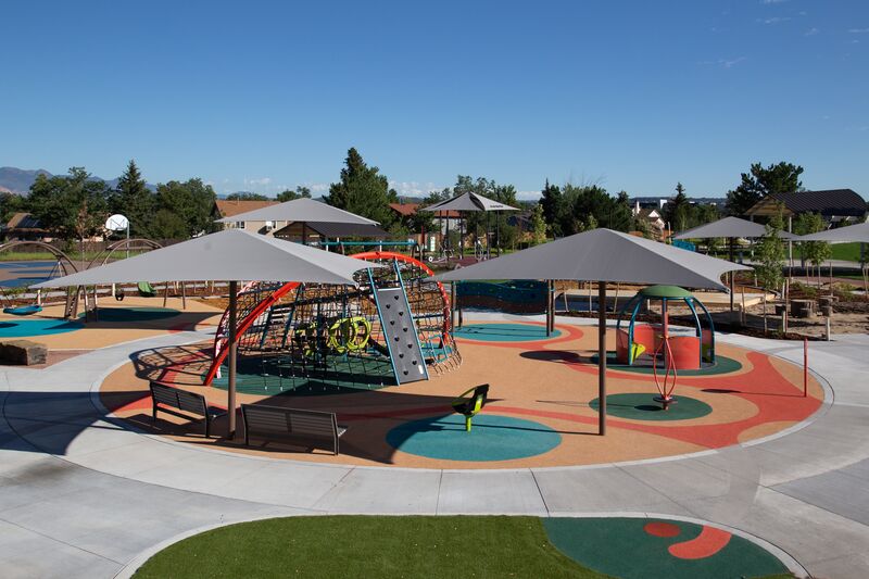 A children's playground in a park with umbrellas.