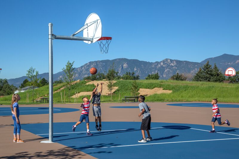 A group of kids playing basketball on an outdoor court.
