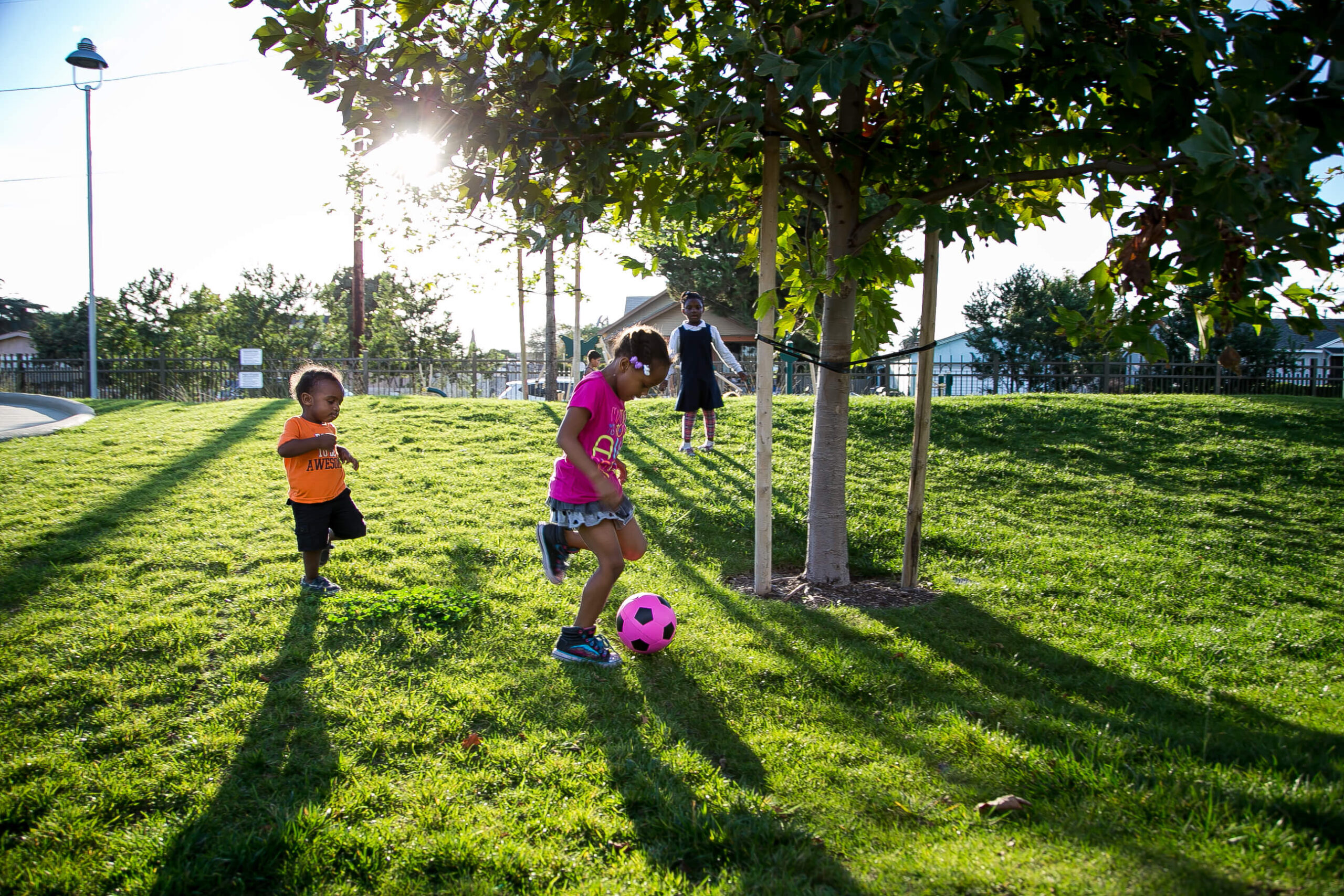 A group of children kicking a soccer ball in a park.