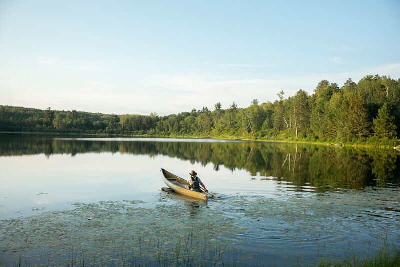 A man is paddling a canoe on a lake.