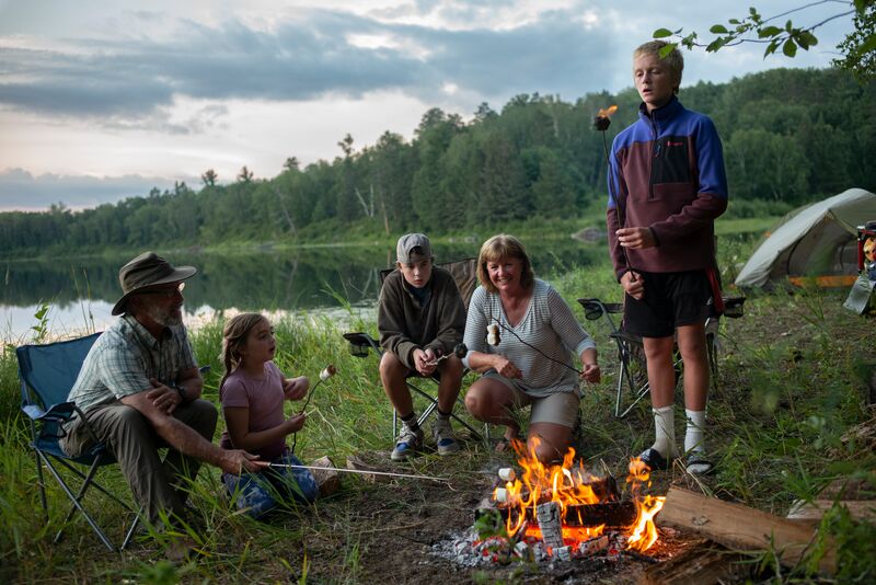 A group of people sitting around a campfire near a lake.