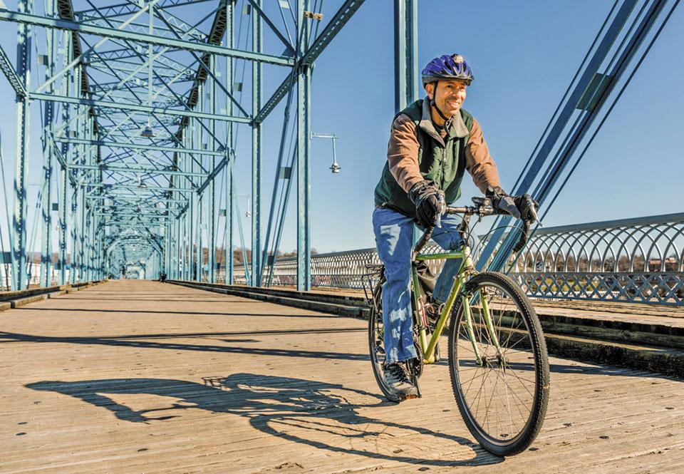 A man riding a bicycle on a bridge.