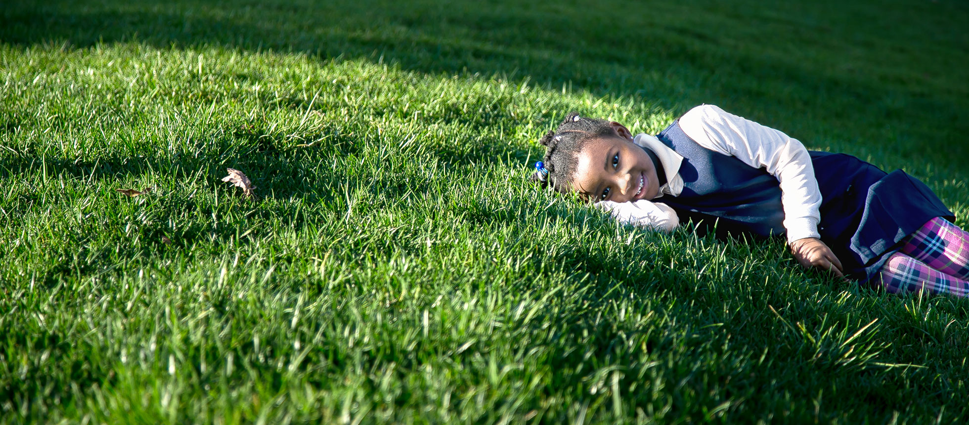 A little girl laying in the grass.