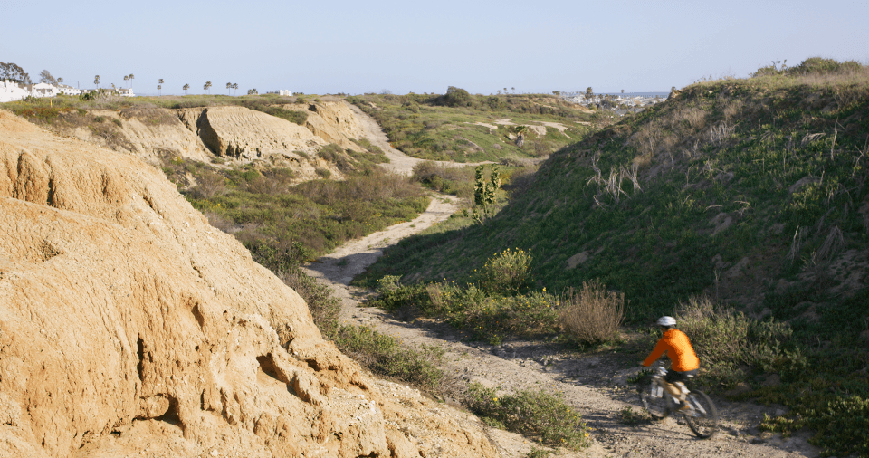 A person rides a bike on a gravel path at Banning Ranch