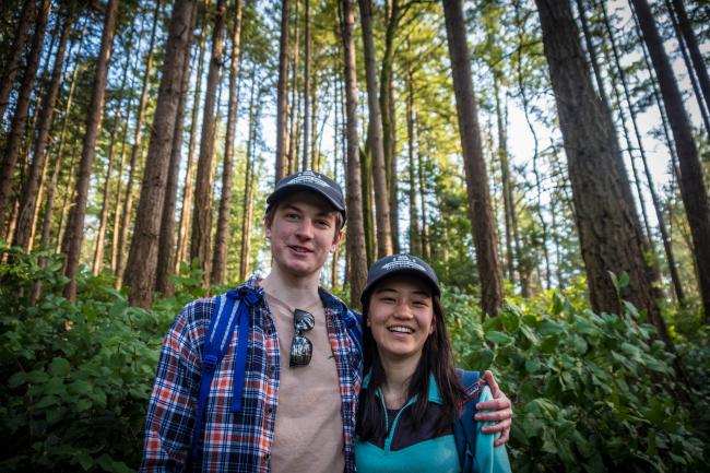Two hikers in their 20s smile for a photo in a forest