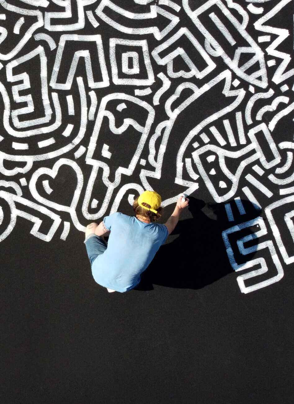 Keith haring's doodles on a black pavement.