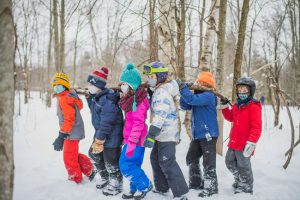 A group of kids in ski gear standing in the snow.