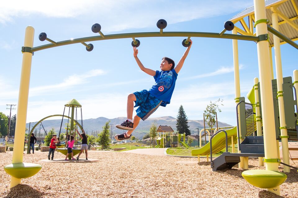 A boy swings on a playground in the sun