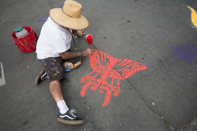Artist Santiago Jaramillo paints a butterfly on pavement